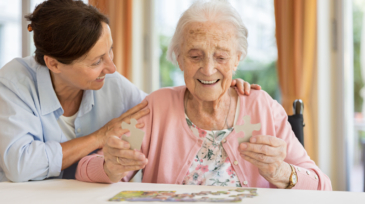 Happy senior woman in wheelchair with caregiver